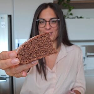la torta alle nocciole e cacao senza glutine Elena Celiachia Stanca ne tien in mano una fetta