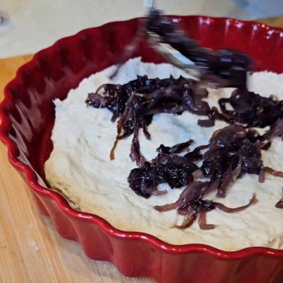 Le cipolle cotte caramellate vengono messe sopra alla focaccia senza lgutine cruda