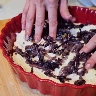 L ecipolle vengono incorporate nell'impasto crudo della focaccia senza lgutine facendo con le dita i tipici buchini della focaccia