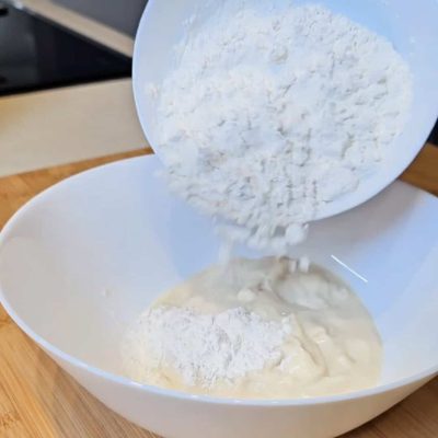 Farina senza glutine versata in ciotola per pane veloce allo yogurt.