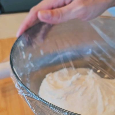Impasto per pane con uvetta senza glutine che lievita coperto da pellicola