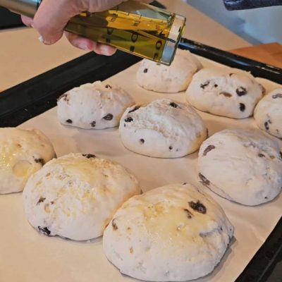 La superfice delle pagnotte di pane senza lgutine con uvetta viene oliata prima della cottura