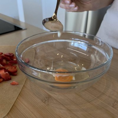 aggiungo uovo nella ciotola per fare i pancakes alle fragole senza glutine e senza latte